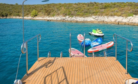 View from a luxury yacht boarding deck with wooden decking and inflatables tied to the water