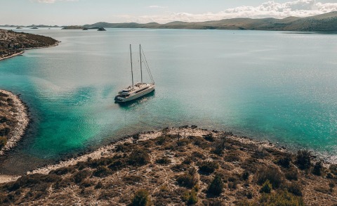 Maxita yacht anchored in a small turquoise bay with rocky shoreline