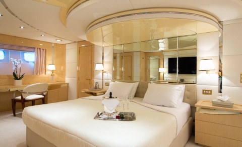 O'Natalina luxury yacht cabin interior with plush bed, mirrored walls, and warm lighting