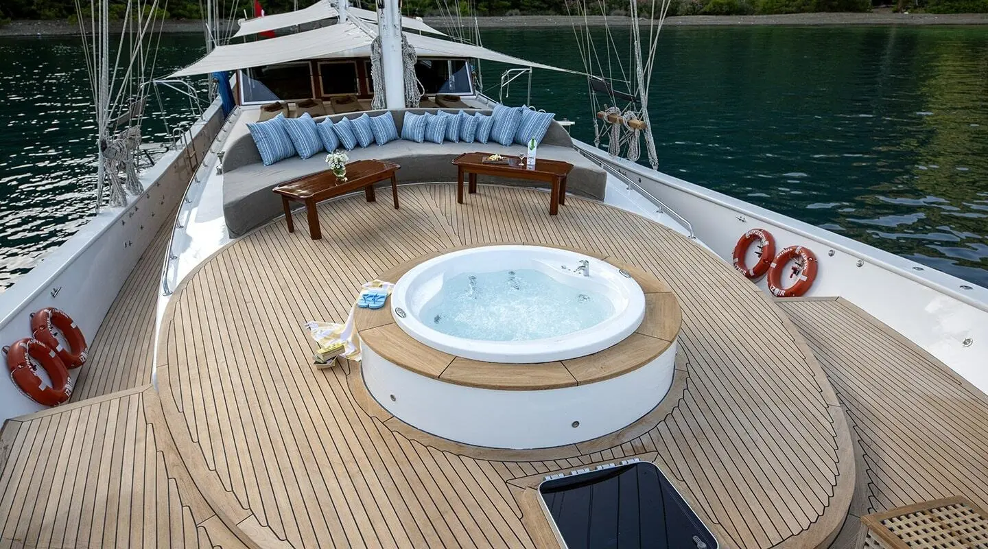 Kayhan Kaptan yacht deck with circular hot tub, sun loungers, and scenic water