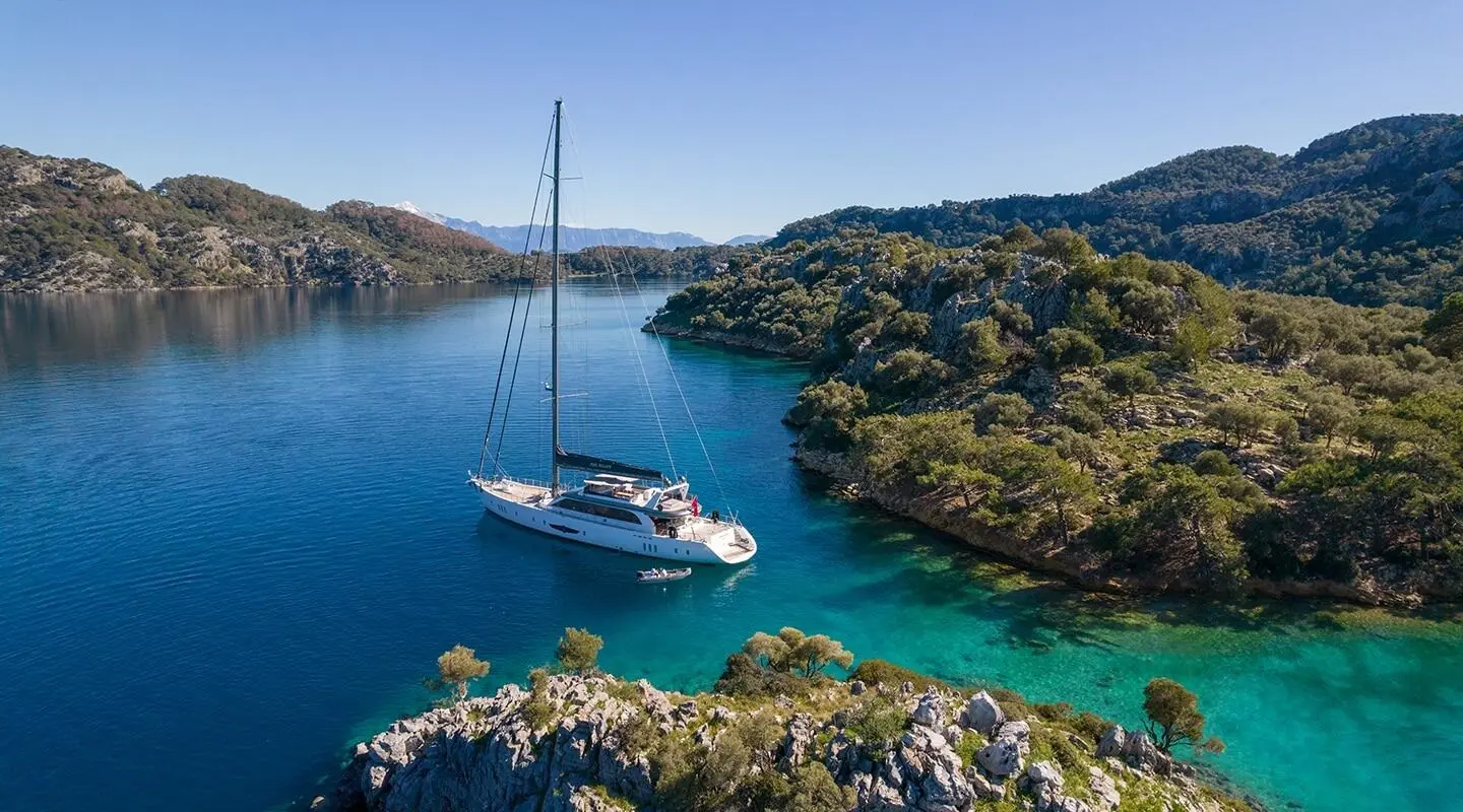 Long Island luxury yacht anchored near rocky turquoise bay at sunset