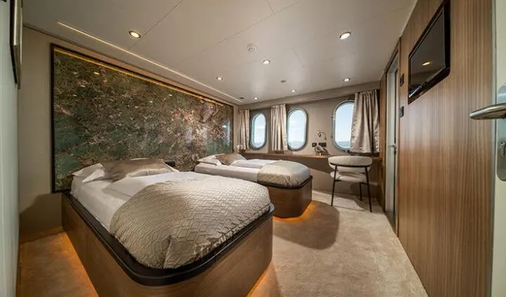 Luxurious wooden cabin aboard Olimp yacht with two beds and portholes