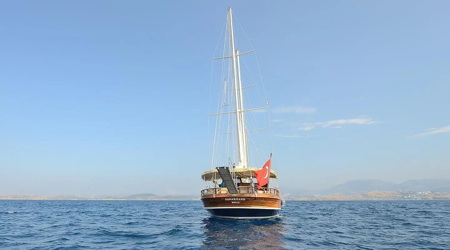 Yacht Samarkand sailing calm sea at sunset with crew on deck