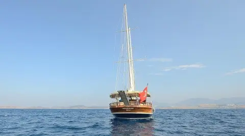 Yacht Samarkand sailing calm sea at sunset with crew on deck