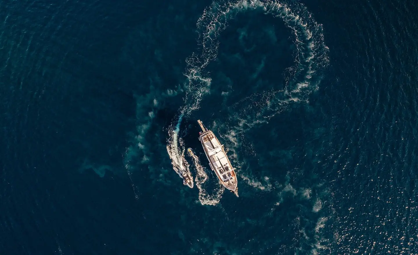 Aerial view of Maske yacht cruising through deep blue sea with wake circling the vessel