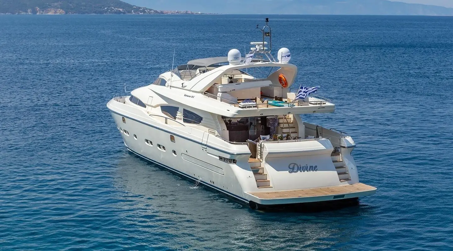 Luxury yacht Divine anchored with passengers on deck under sunny blue sky