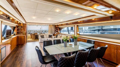 Indoor yacht living area with wood cabinets, glass dining table and floral decor