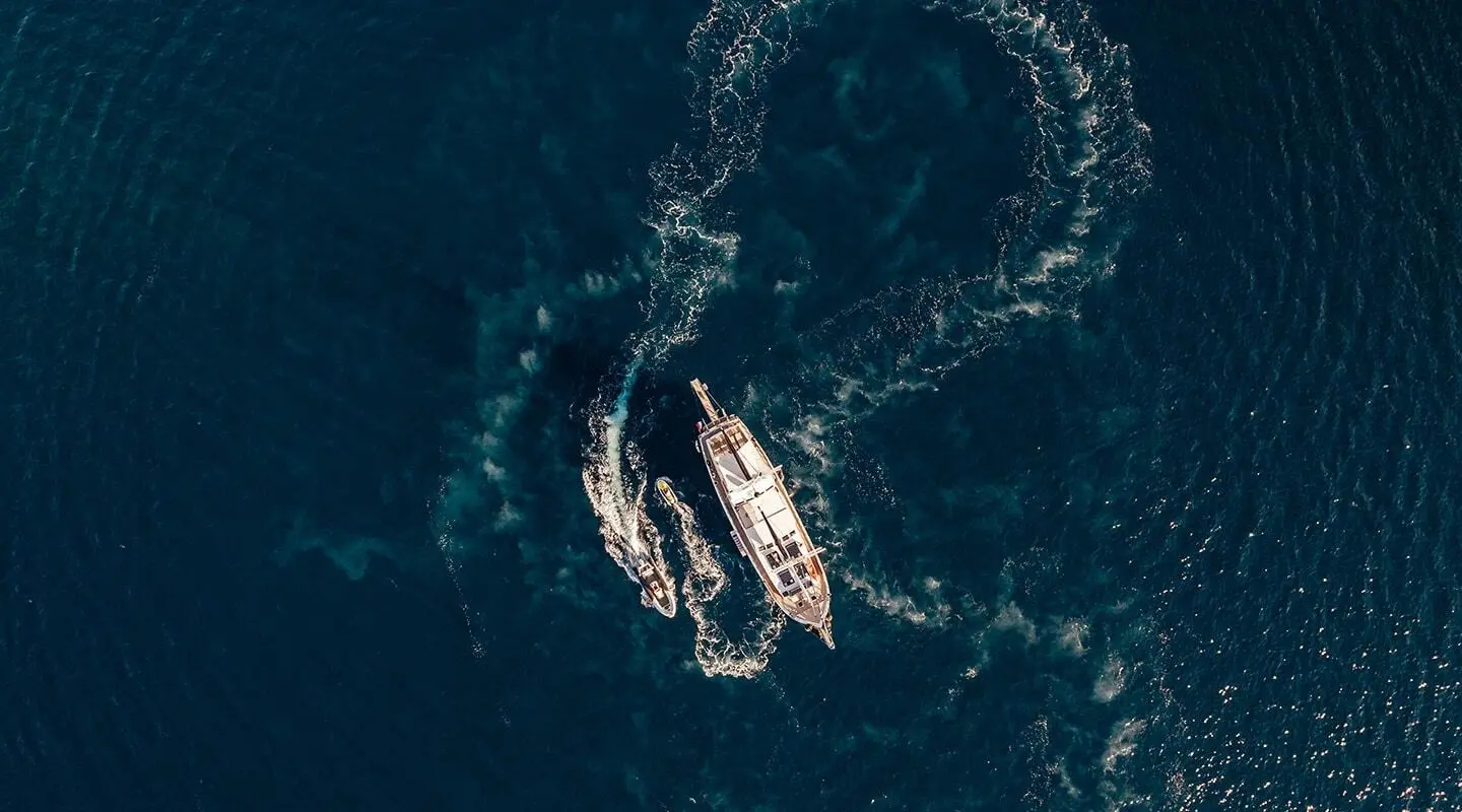 Top-down view of a luxury yacht Maske anchored in dark blue sea at sunset