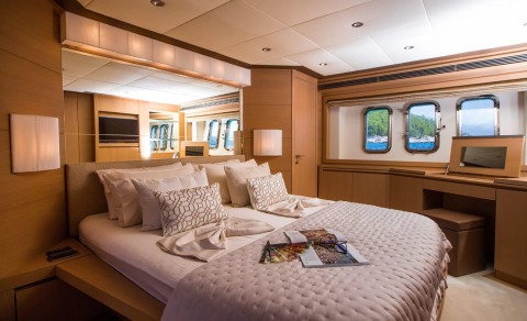Salt luxury yacht cabin with plush bed, neutral tones, pillows, and port window view