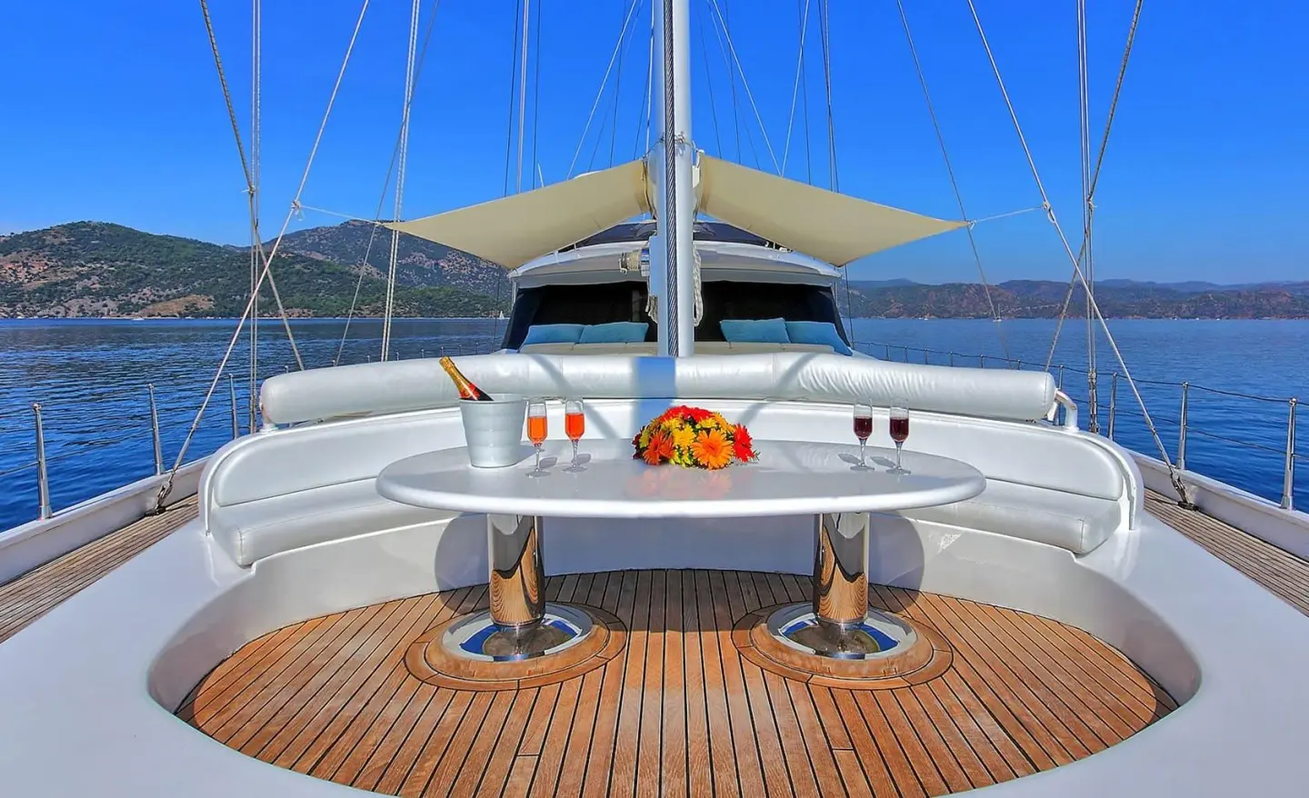 Angelo II yacht deck with seating, wooden flooring, and calm sea view at sunset