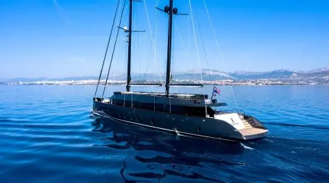Two-masted motor yacht cruising on blue sea with distant coastline