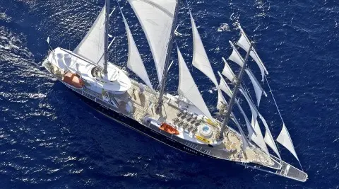 Yacht named Running on Waves sails at sunset on blue sea with multiple masts