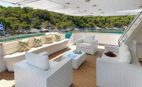 Idylle yacht upper deck seating area with white cushioned chairs and coffee table