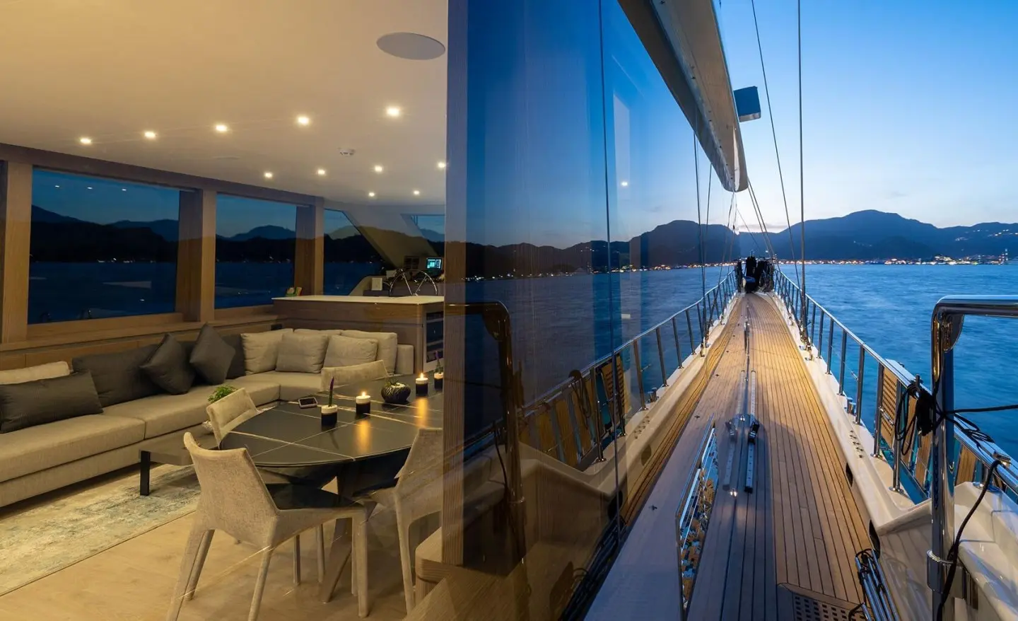 Evening yacht Good Life reflecting lights on sleek blue hull beside calm water