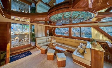 Luxurious wooden yacht salon with beige seating and large windows showing the exterior