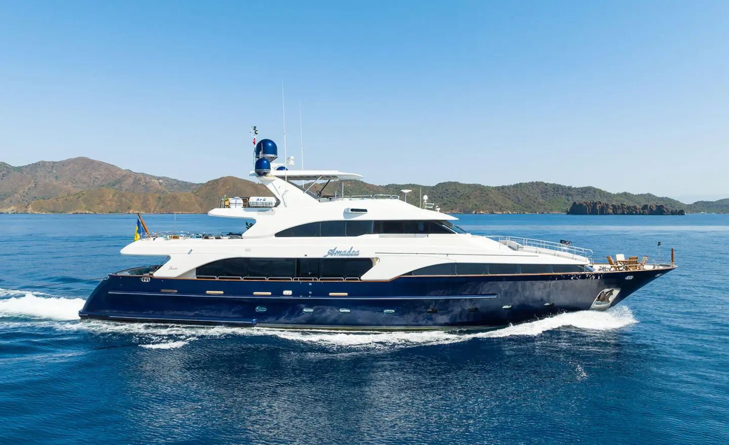 Amadea yacht cruising on blue sea with clear sky and distant coastline