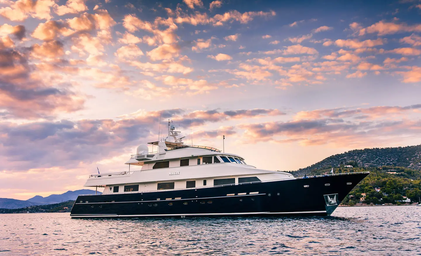 Luxury motor yacht Magix moored on calm water under sunset sky