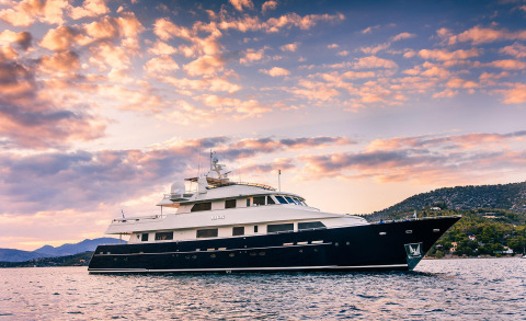 Magix luxury yacht anchored on calm sea with sunset sky and distant coastline