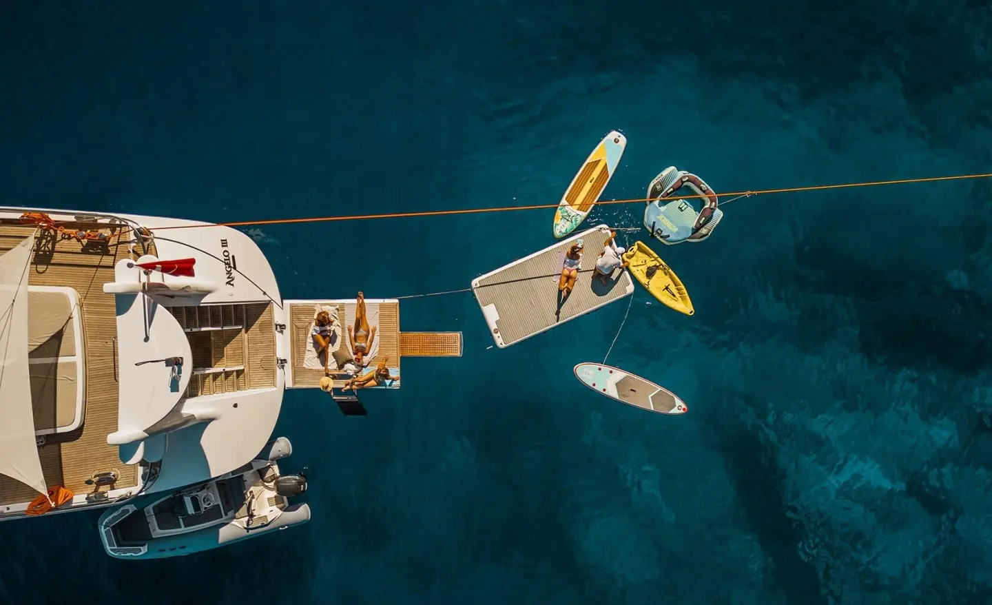 Angelo III yacht anchored with two dinghies beside a wooden jetty at sunset