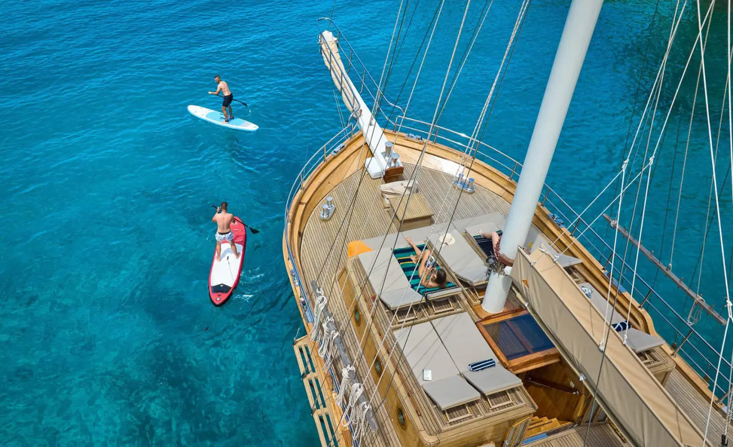 Libra luxury yacht deck above turquoise sea with aerial view, sun loungers and rigging