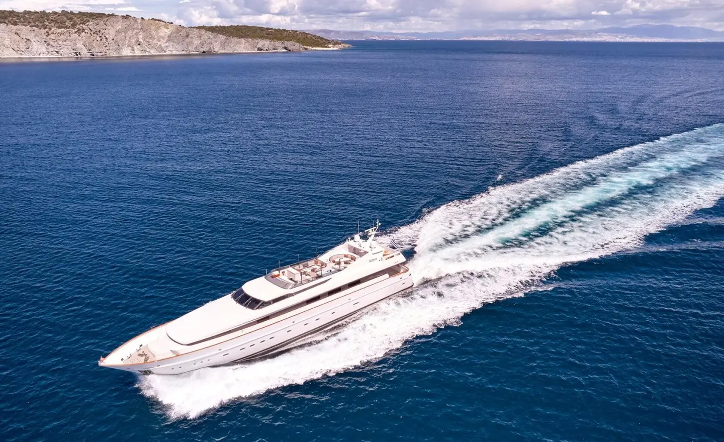 Mobius motor yacht cruising on blue sea with wake behind, clear sky
