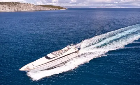 Mobius motor yacht cruising on blue sea with wake behind, clear sky