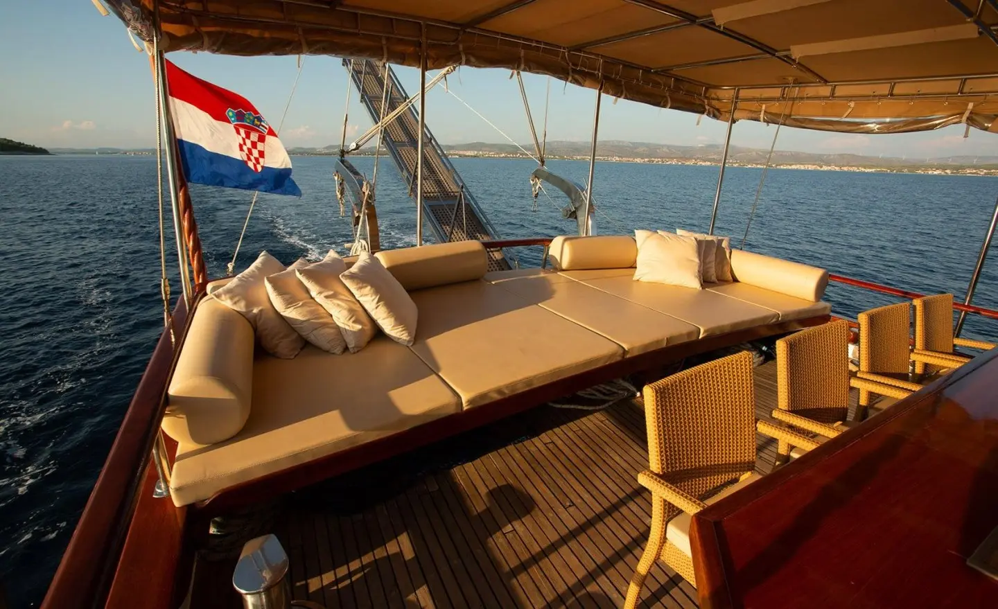 Sunlit yacht cockpit with tan cushions and wooden railings at sea