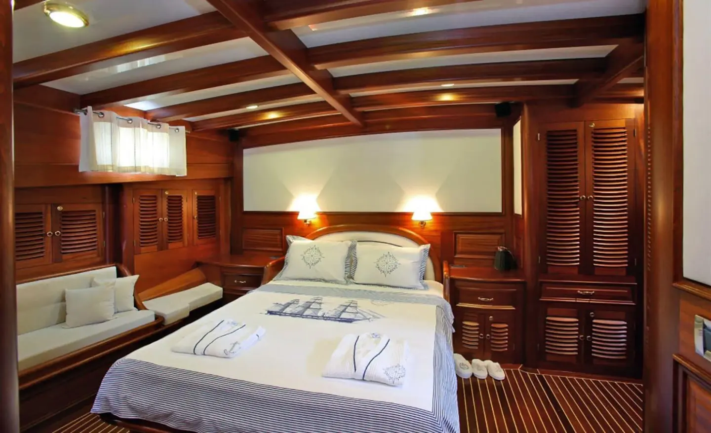 Kaya Guneri 4 yacht interior cabin with bed and wooden cabinetry at sunset