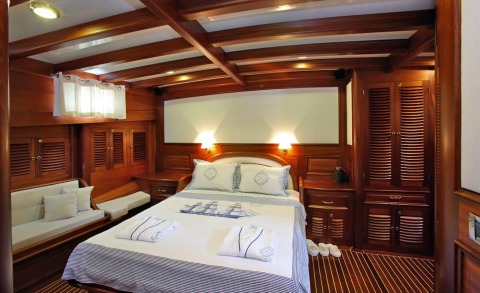 Kaya Guneri 4 luxury yacht cabin with wooden paneling, bed and seating area