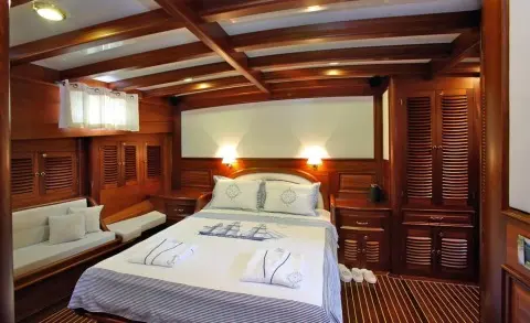 Kaya Guneri 4 yacht interior cabin with bed and wooden cabinetry at sunset