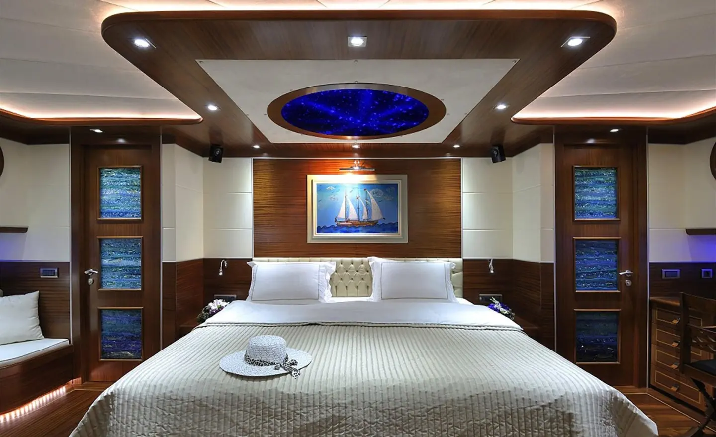 Dolce Mare yacht cabin interior with large bed, wooden shelves, and framed art