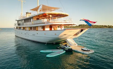 Large white yacht Bellezza docked near the shoreline with a gangway