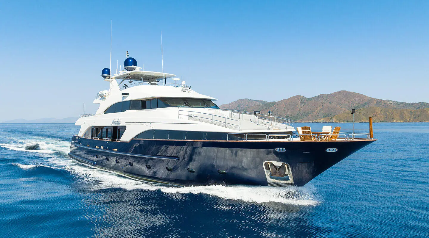 Amadea yacht sailing, white hull cutting blue water with wake
