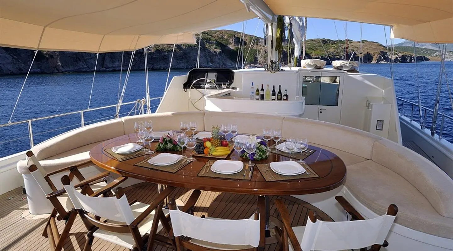 Dolce Mare yacht deck with wooden table set for dining under a canopy