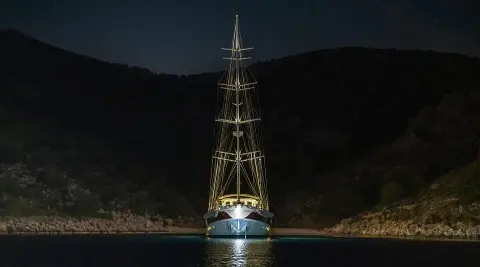 Gulet Tersane 8 at night, illuminated mast and sails, anchored in calm water