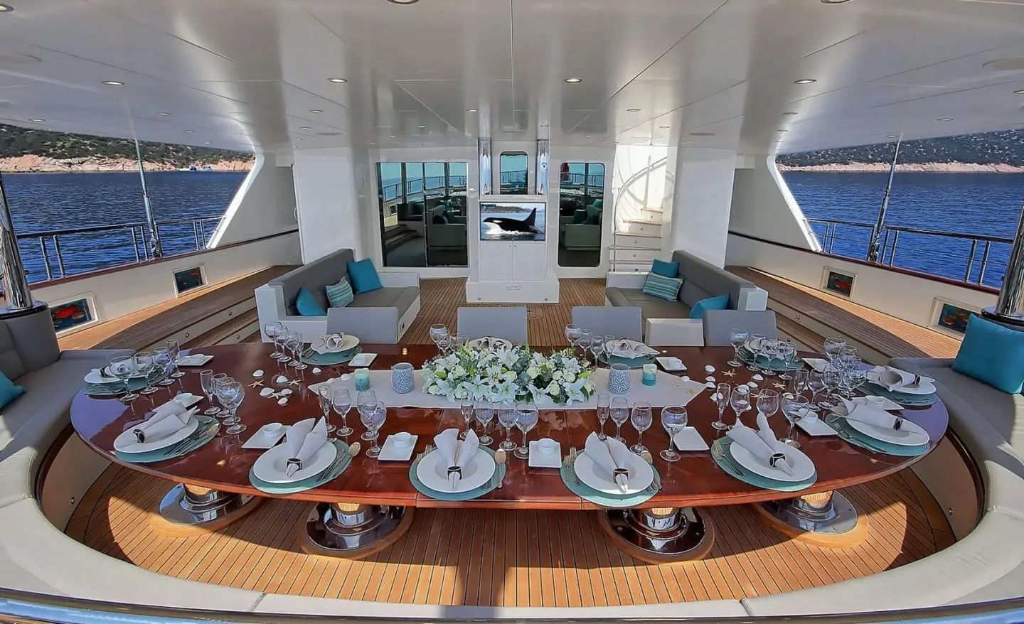 Meira yacht dining deck with long table set for guests and plates