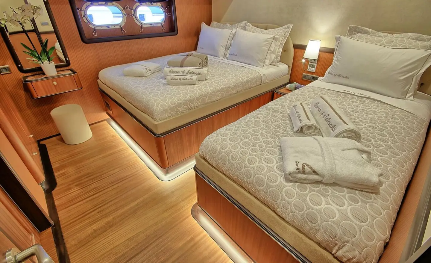 Queen Of Salmakis yacht interior with triple cabin, two beds, wooden floor, soft lighting