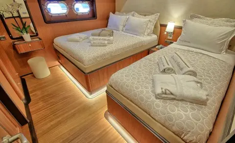 Queen Of Salmakis yacht interior with triple cabin, two beds, wooden floor, soft lighting