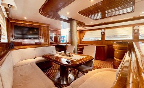 Wood-paneled interior with a rounded table and seating area, television mounted on wall