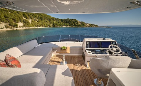 Hideaway yacht cockpit with seating area, table of apples, and navigation controls facing calm sea