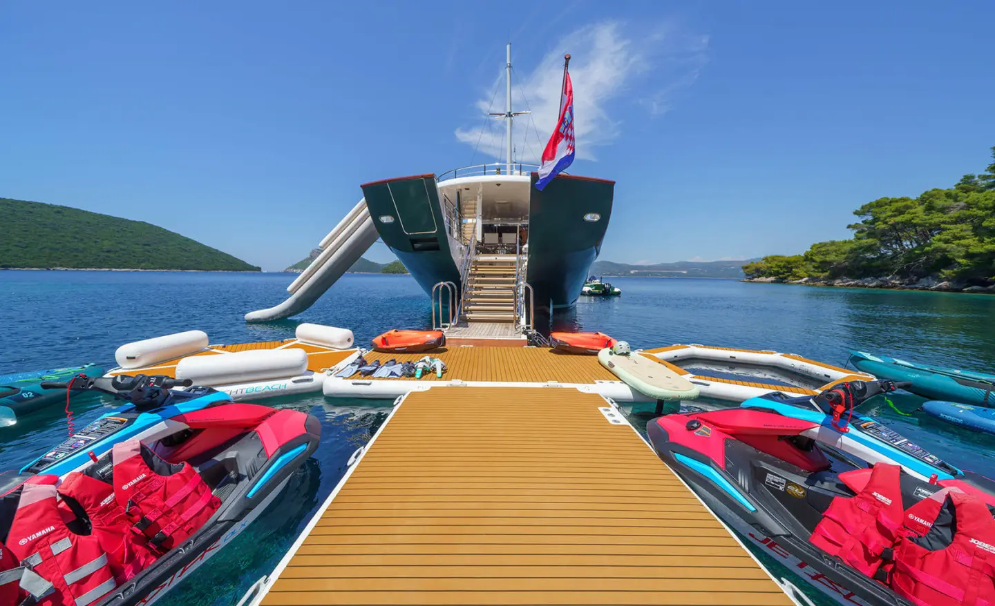 Maia yacht at wooden marina gangway with colorful water toys on sides