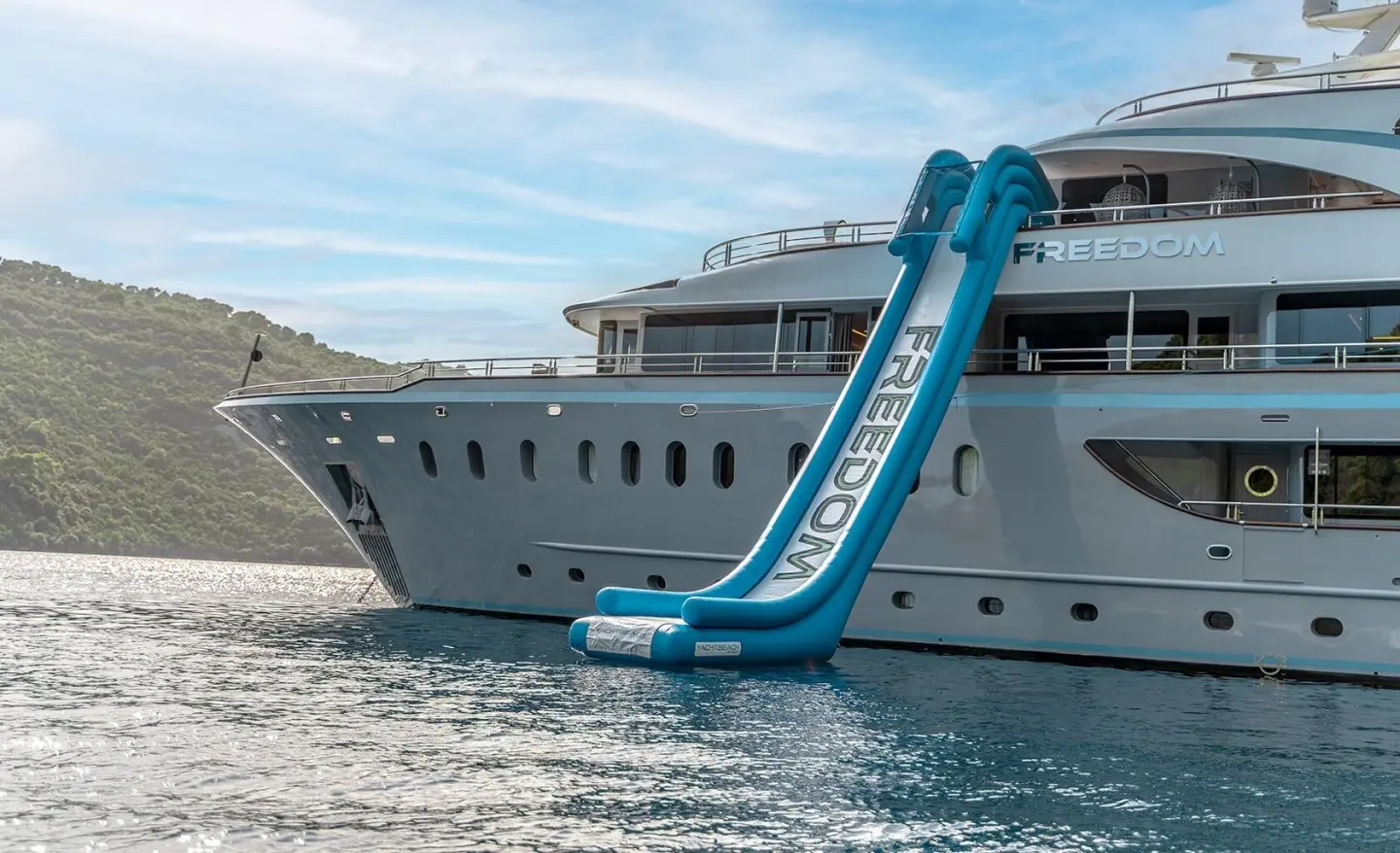 Luxurious yacht Freedom moored on calm water with a blue slide and clear sky