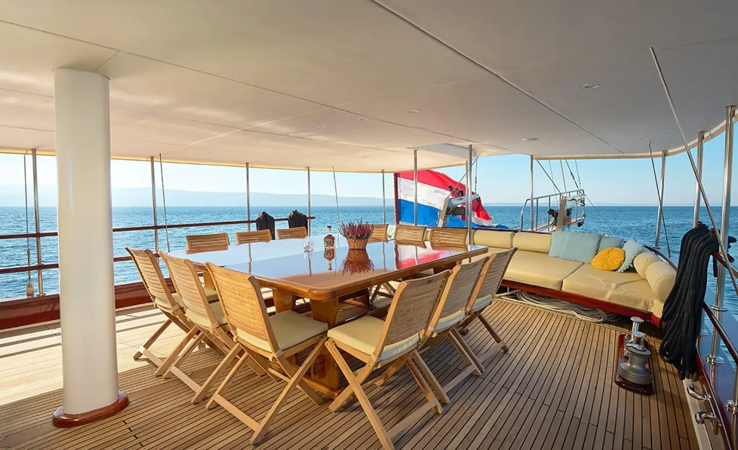 Aft deck of Linda gulet with wooden chairs and table set on deck near railing