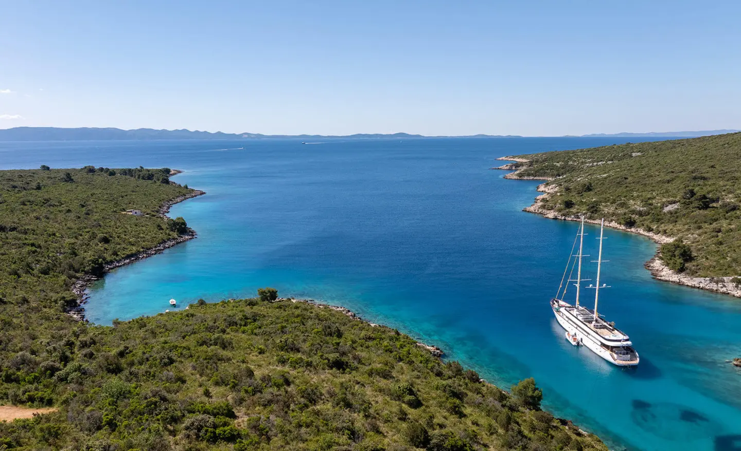 Blue turquoise water with a large sailing yacht anchored near shore