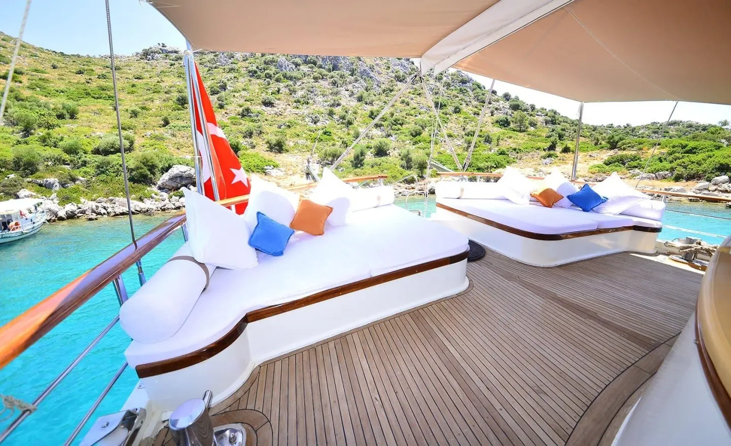 White cushioned seating on an open deck with Turkish flag in the background