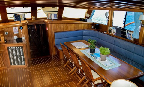 Gulet Enderim A interior with wooden surroundings, a table, and blue cushioned seating