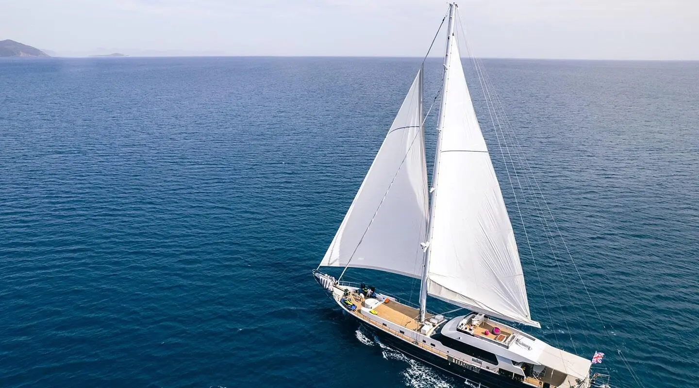 Yacht Good Life sails on calm sea at sunset with white sails catching breeze