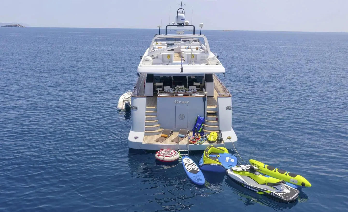 Oversized luxury yacht Grace anchored with small boats beside in calm blue sea