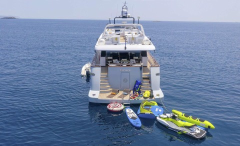 Rear view of Grace yacht with water toys docked around on clear sea