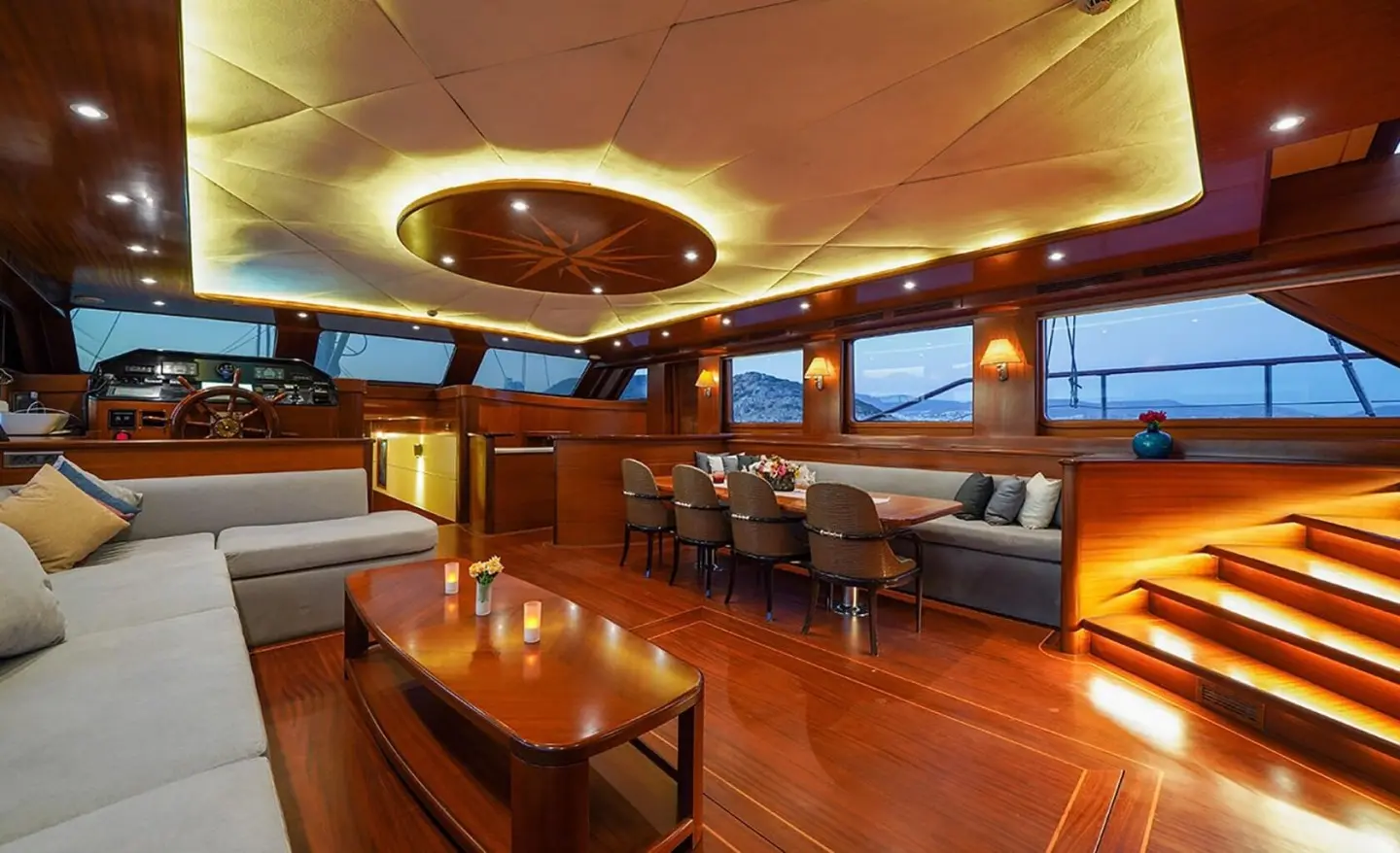 Interior of a yacht salon with wood floors, seating, and warm lighting